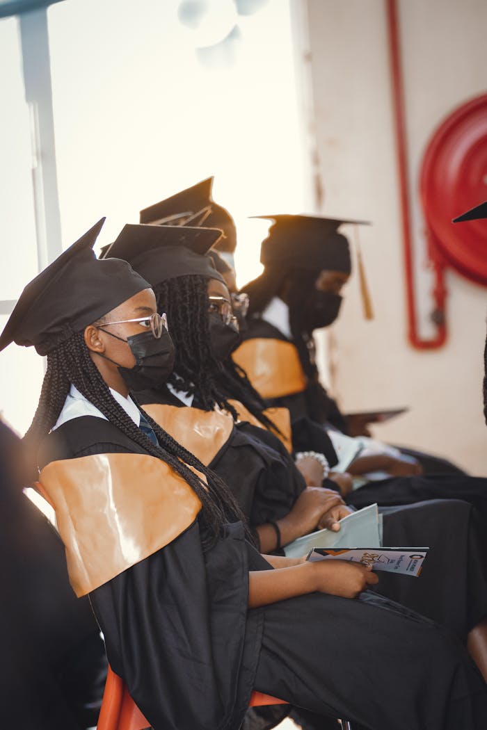 services-01 Students in graduation caps and gowns seated indoors during a ceremony in Nairobi.