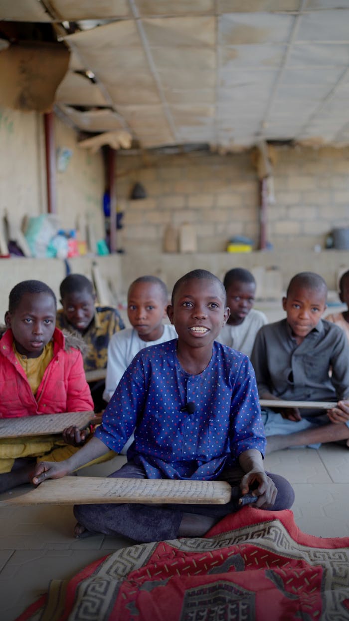 services-02 A group of smiling children engaged in a classroom activity, sitting on rugs indoors.