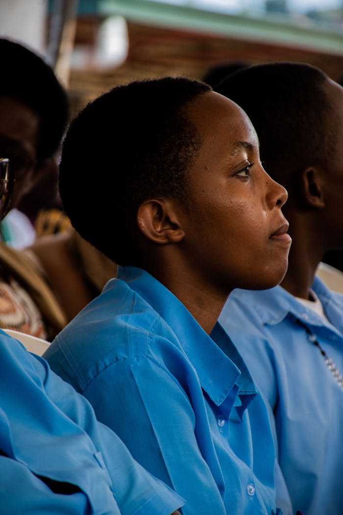 about-us-02 A group of students in blue uniforms attentively listening during a class session.